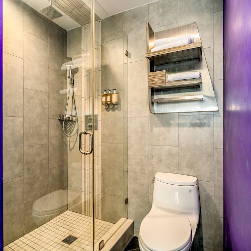 A modern bathroom with a shower, toilet, and tiled walls
