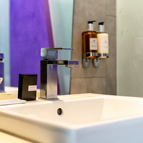 A close-up of a bathroom sink with a modern faucet and toiletries.