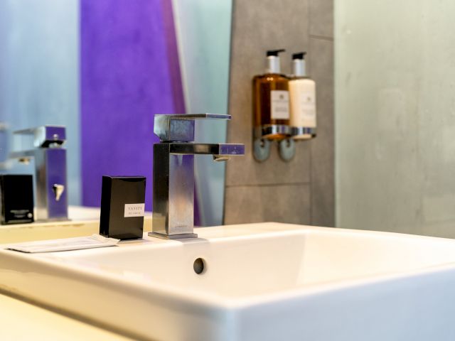 A close-up of a bathroom sink with a modern faucet and soap dispensers.