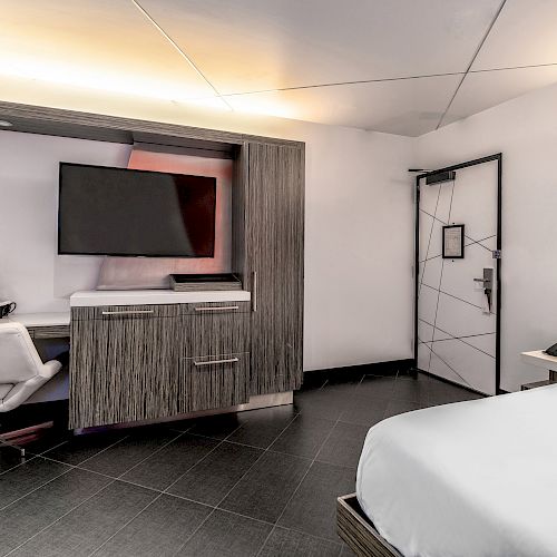 A hotel room with a bed, desk, TV, and door.