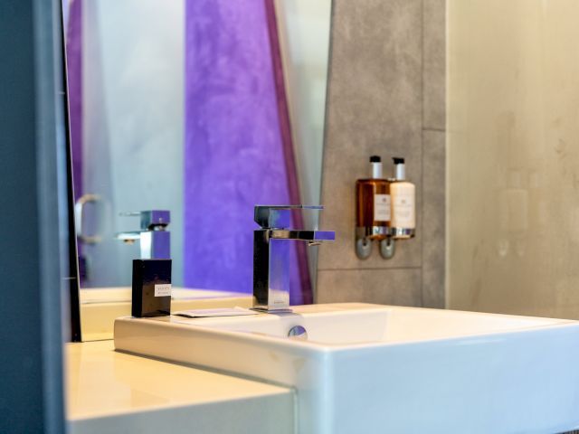 A close-up view of a bathroom sink with a black faucet and a mirror in the background.