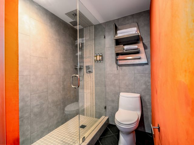 A standard bathroom with a shower, toilet, and tiled walls.