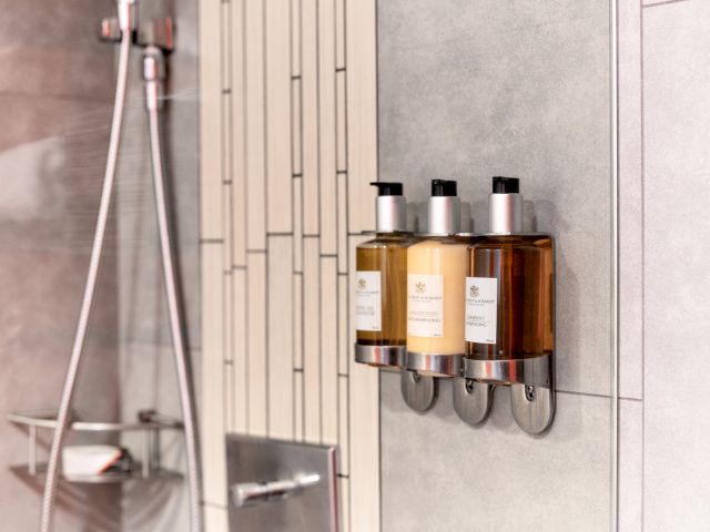 A bathroom with a shower and bottles of soap.