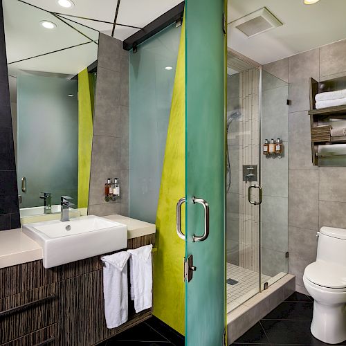 A modern bathroom with a glass shower door, tiled walls, and a modern sink.