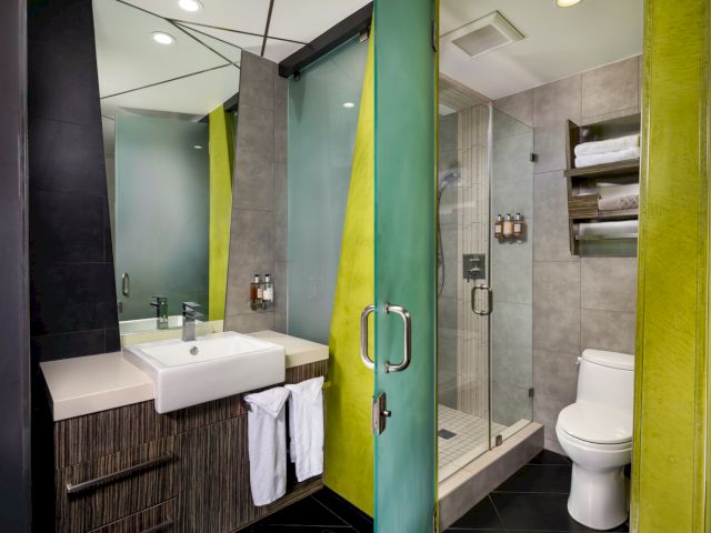 A modern bathroom with a glass-enclosed shower, white sink, and toilet.