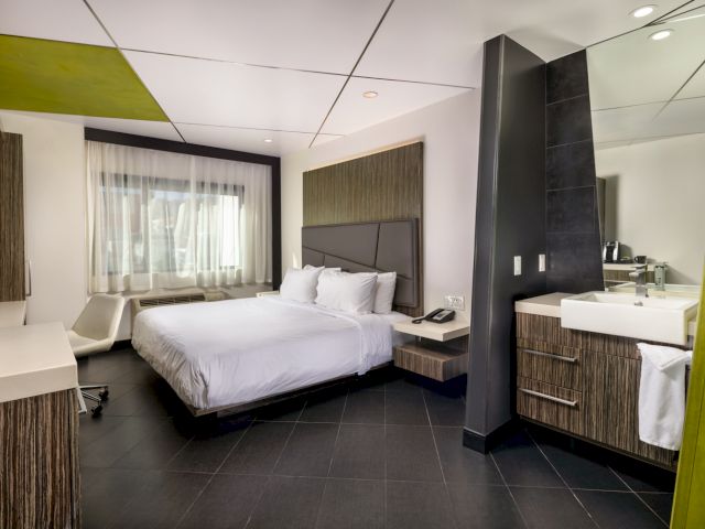 A modern hotel room with a large bed, desk, and bathroom