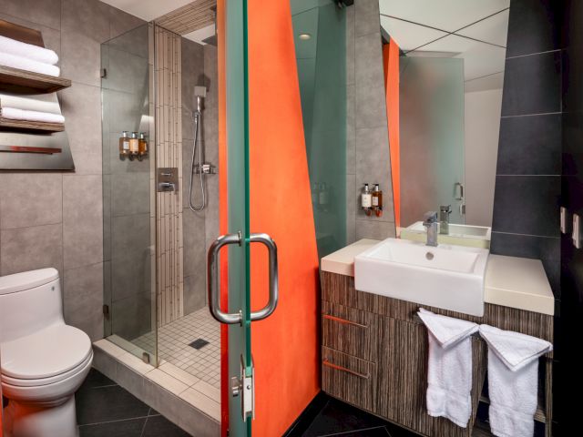 A modern bathroom with a glass-enclosed shower, single sink, and toilet.