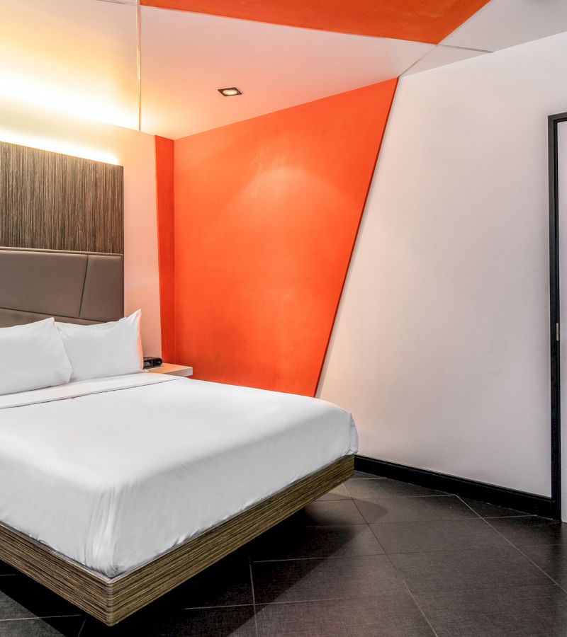 A hotel room with a bed, nightstand, and headboard