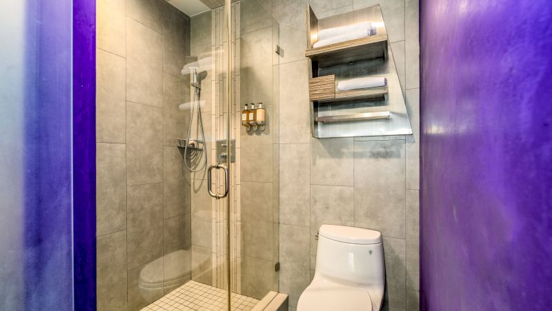 A modern bathroom with a shower, toilet, and tiled walls