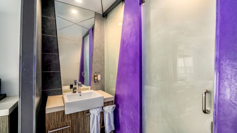 A modern bathroom with a sink, mirror, and shower