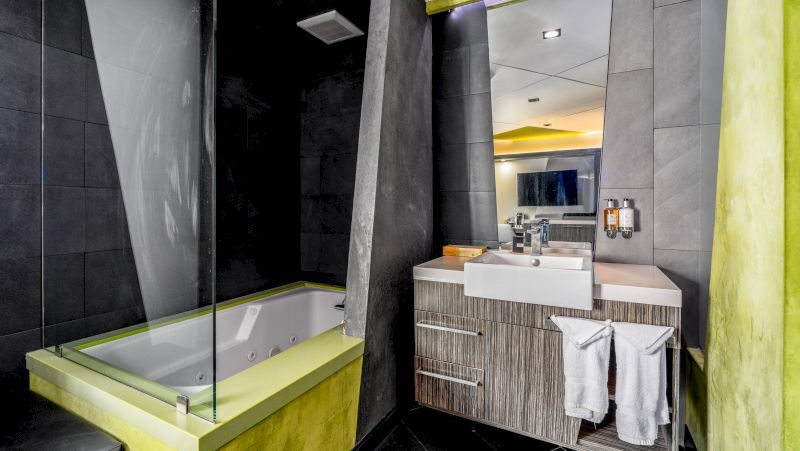 A modern bathroom with a bathtub, sink, and towels.