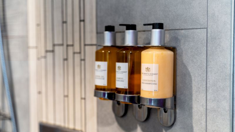 Three bottles of shampoo and conditioner on a bathroom wall