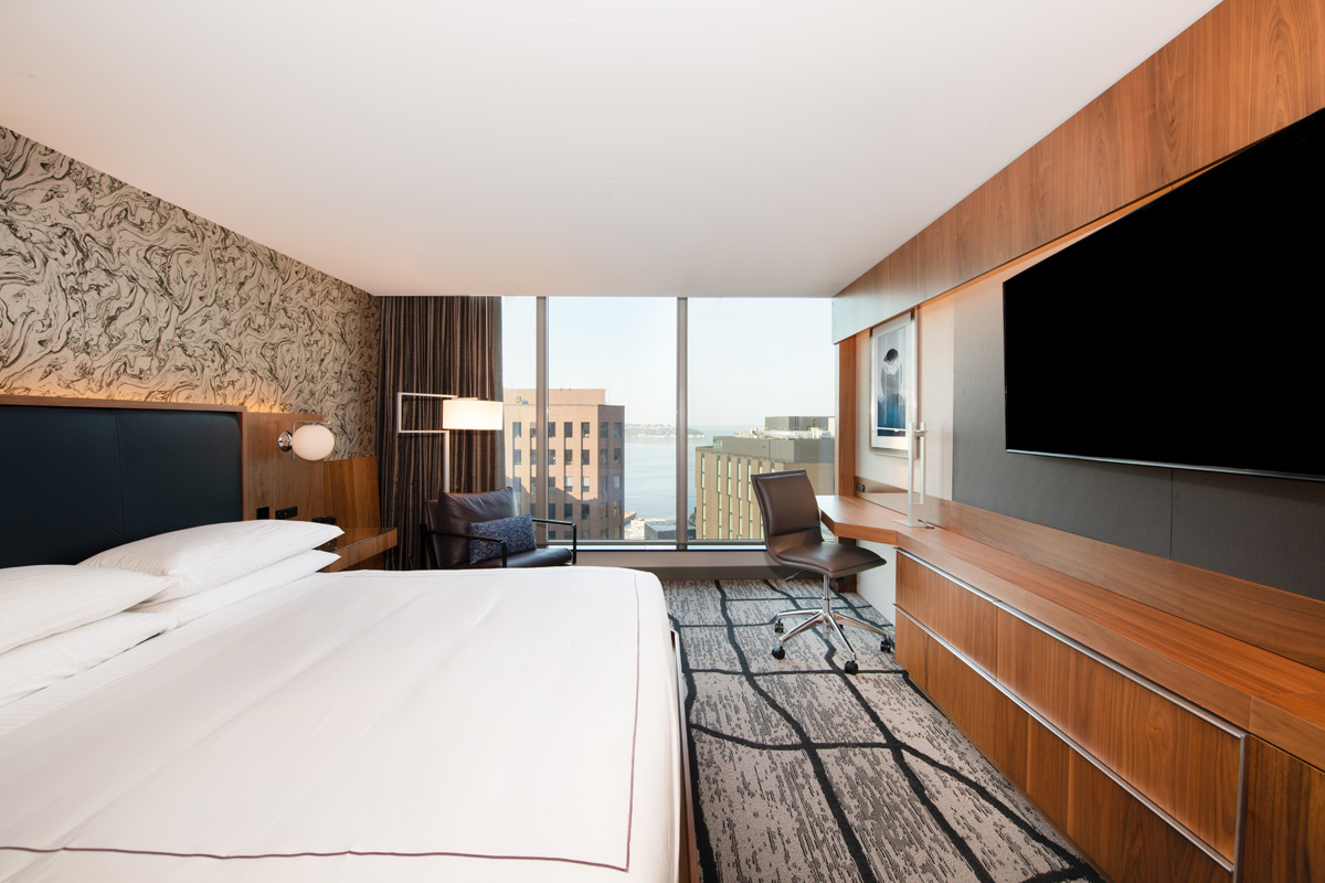 A hotel room with a large bed, desk, and city view.